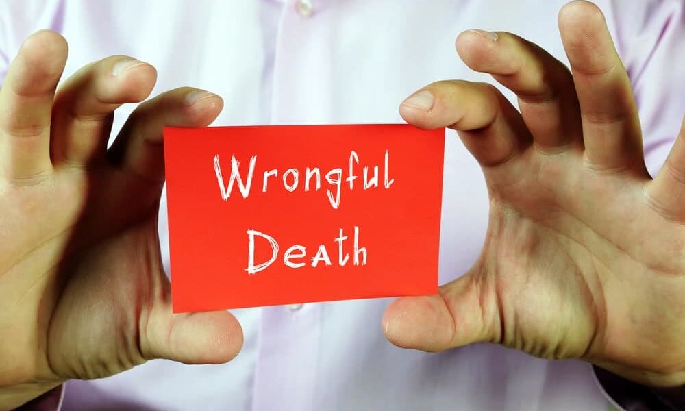 wrongful death lawyer in Greater Kansas City area of Missouri portrayed by man holding a card that says 'wrongful death'